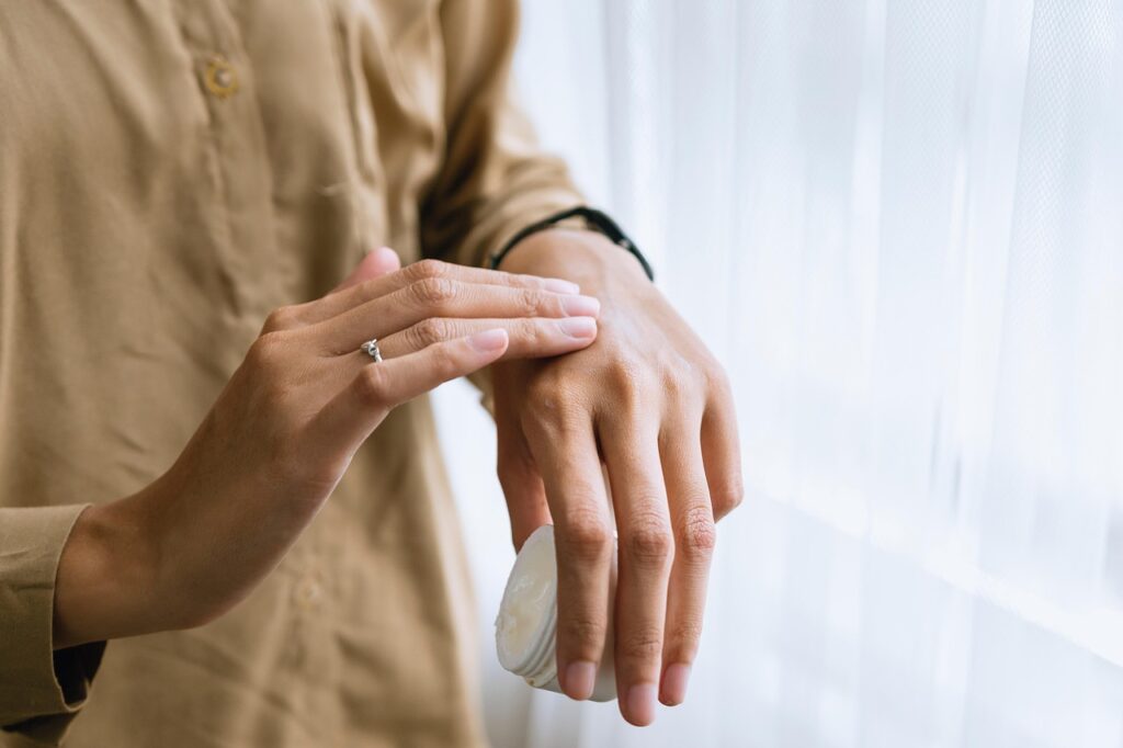 Femme appliquant une crème sur ses mains, soin naturel des ongles